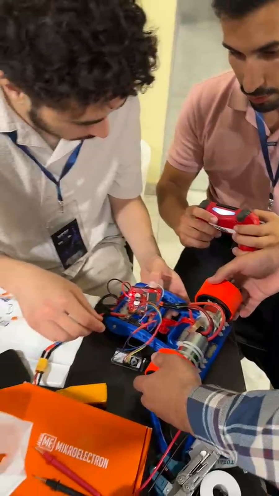 A team testing its robot in the pit, one hand on the controller.