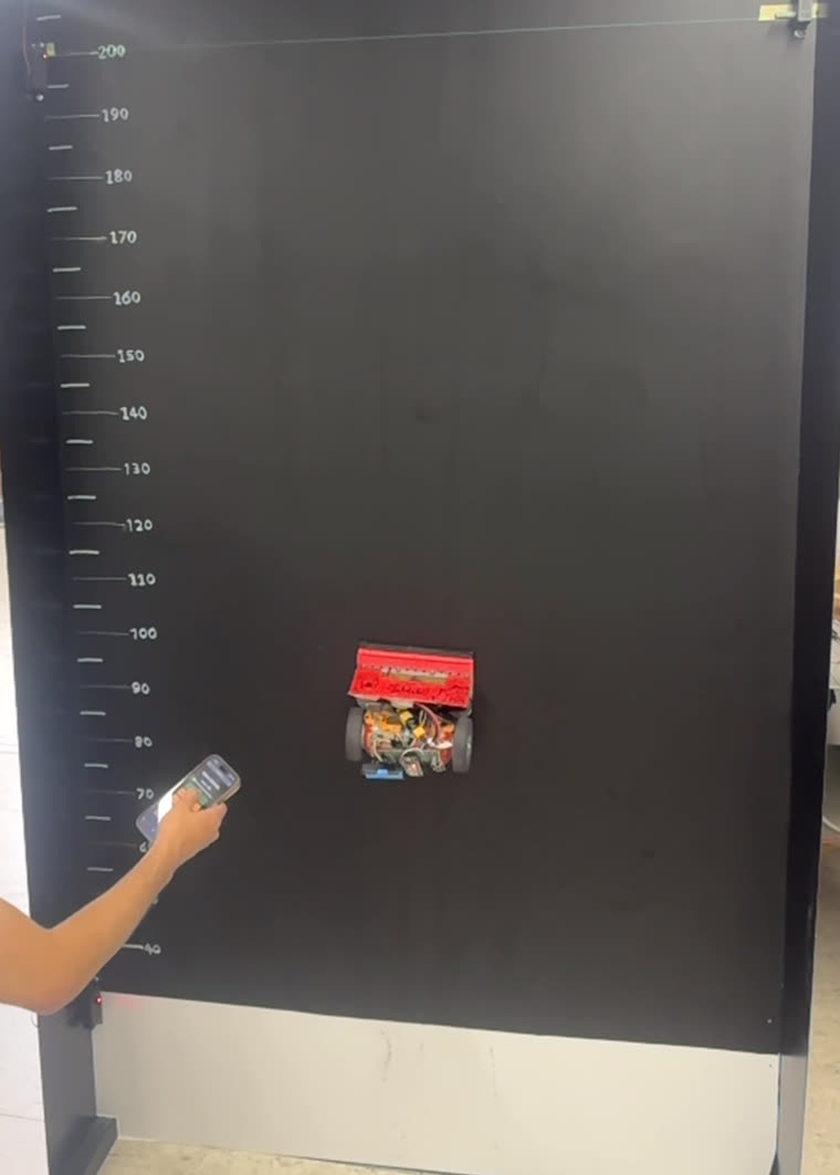 A competing robot holding the real wall at around 90 cm, its driver on the controller below.